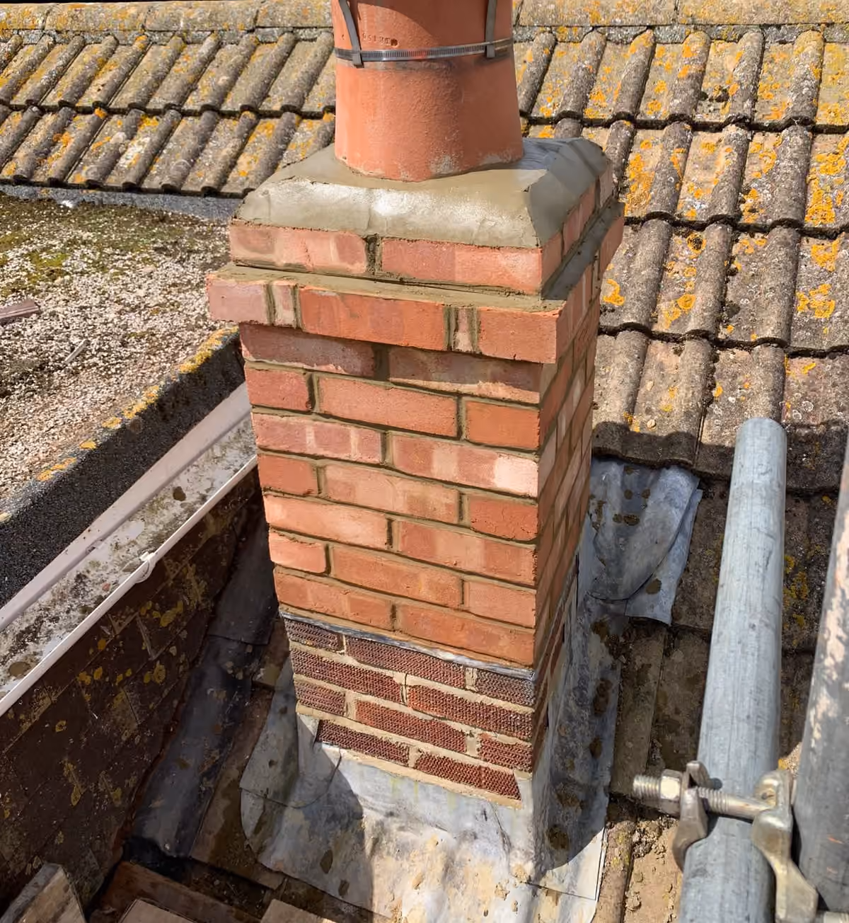 A chimney stack with the surrounding tiles stripped back