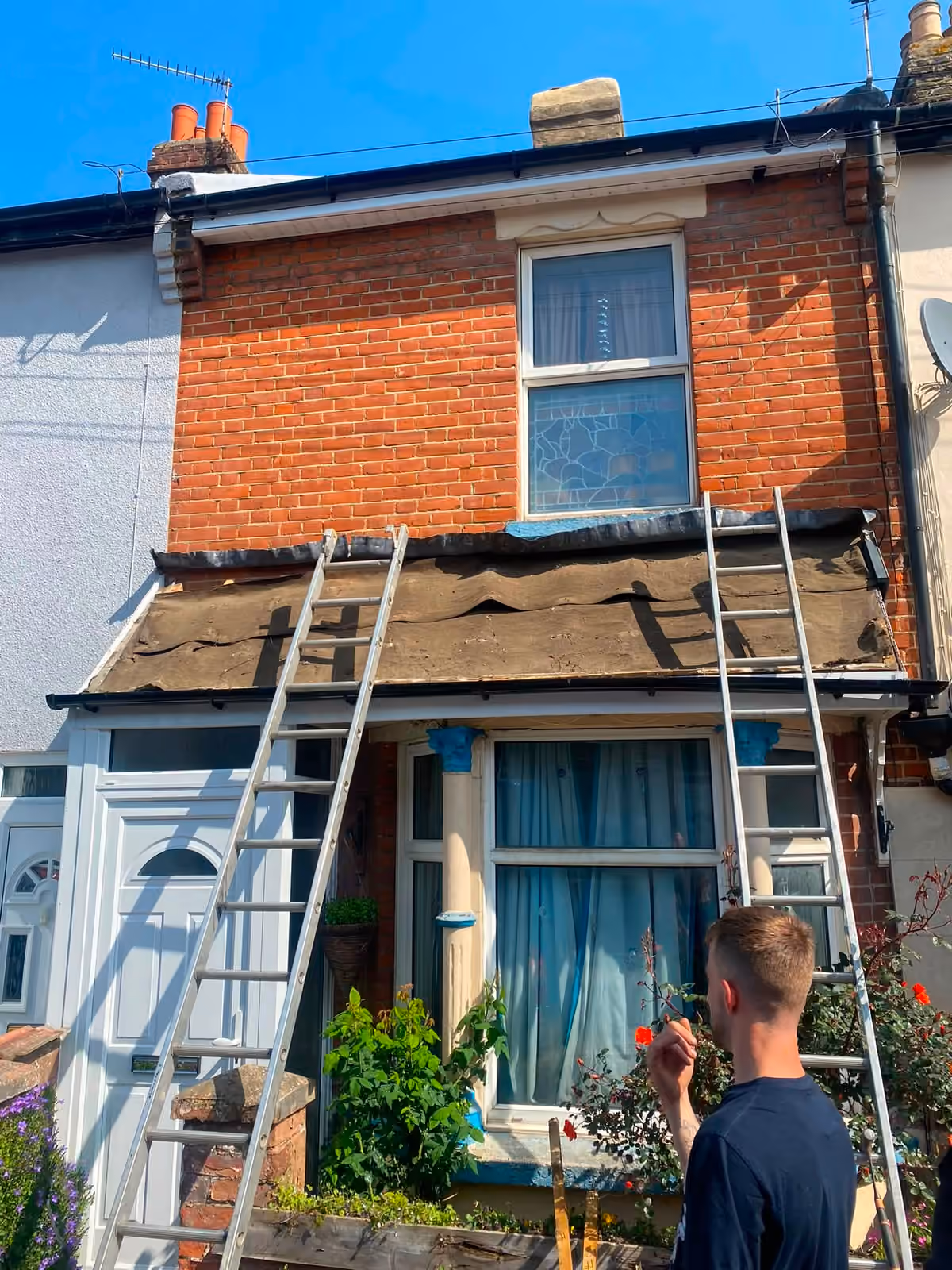 Ladders up against a terraced house with the front slope stripped