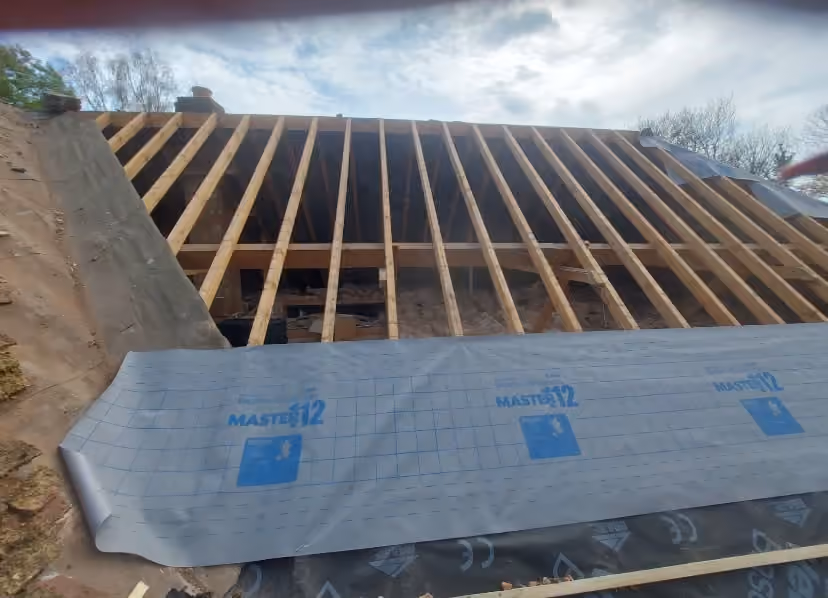 Roof timbers exposed with underlay being drawn across