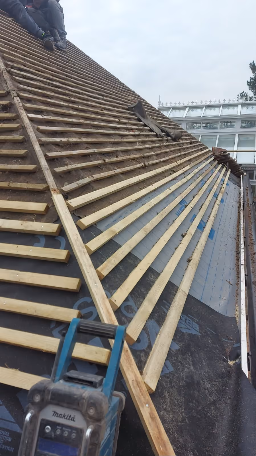 New battens run out along a pitch with a nail gun resting on them