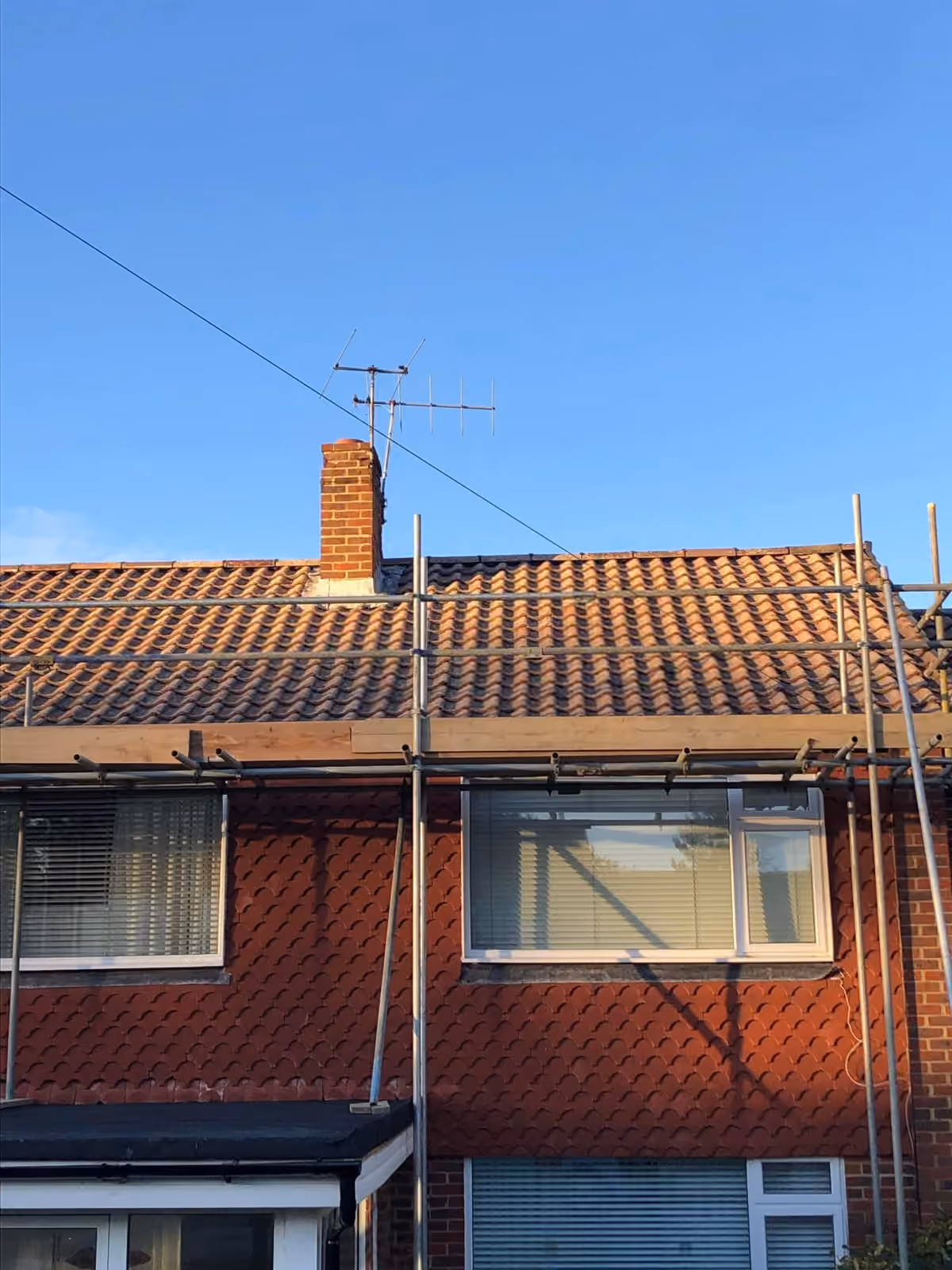 Tiled roof on a pair of semis with scaffold along the eaves