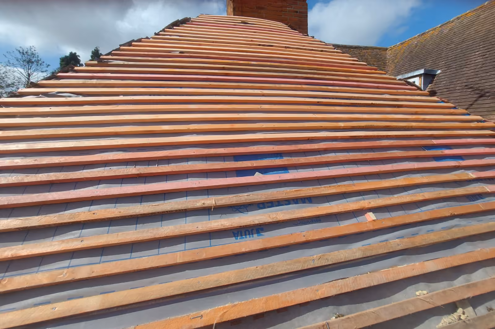 A hip battened out over blue underlay, tiles stacked ready