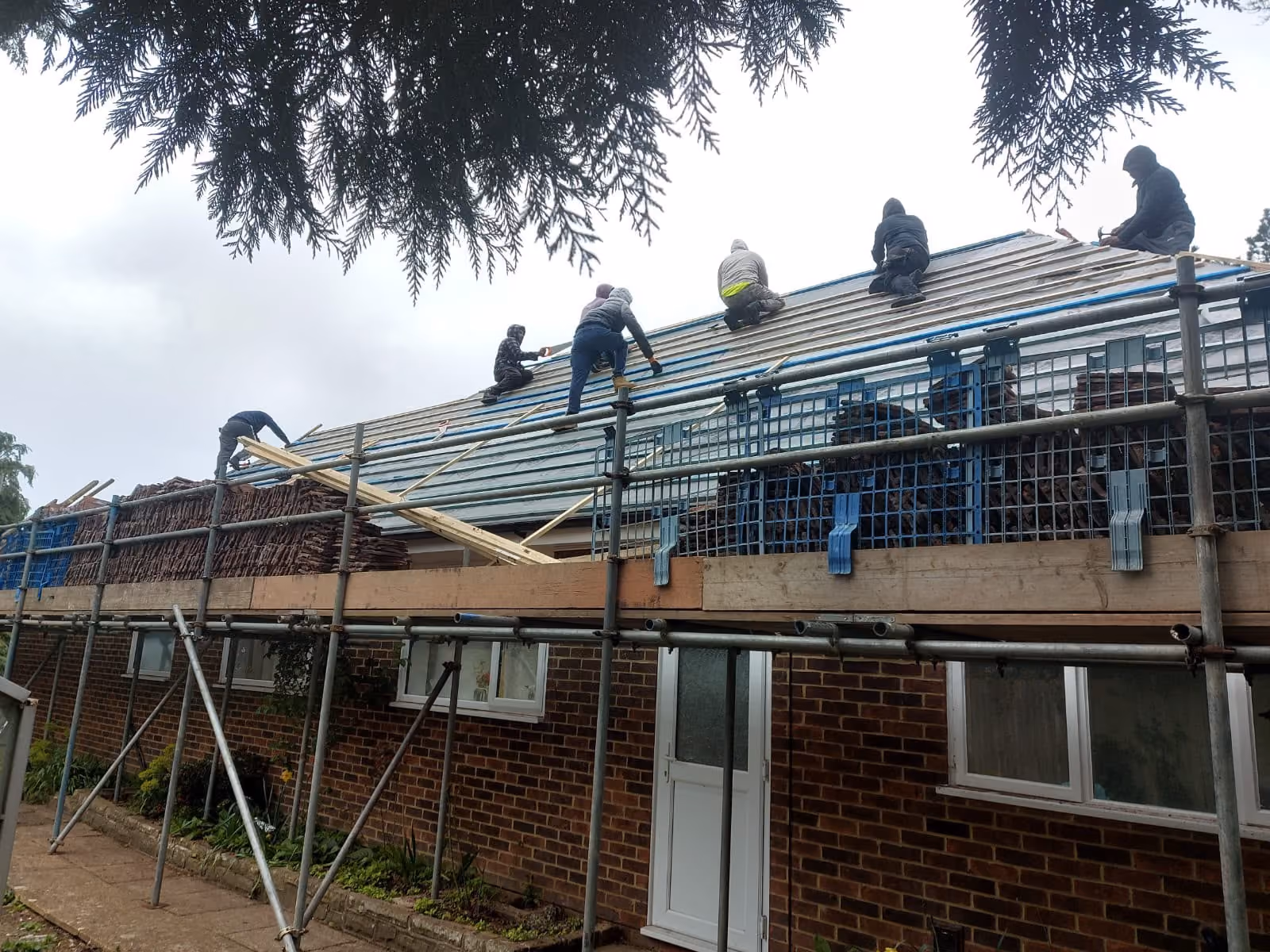 Roofers working along a scaffolded roof with underlay down