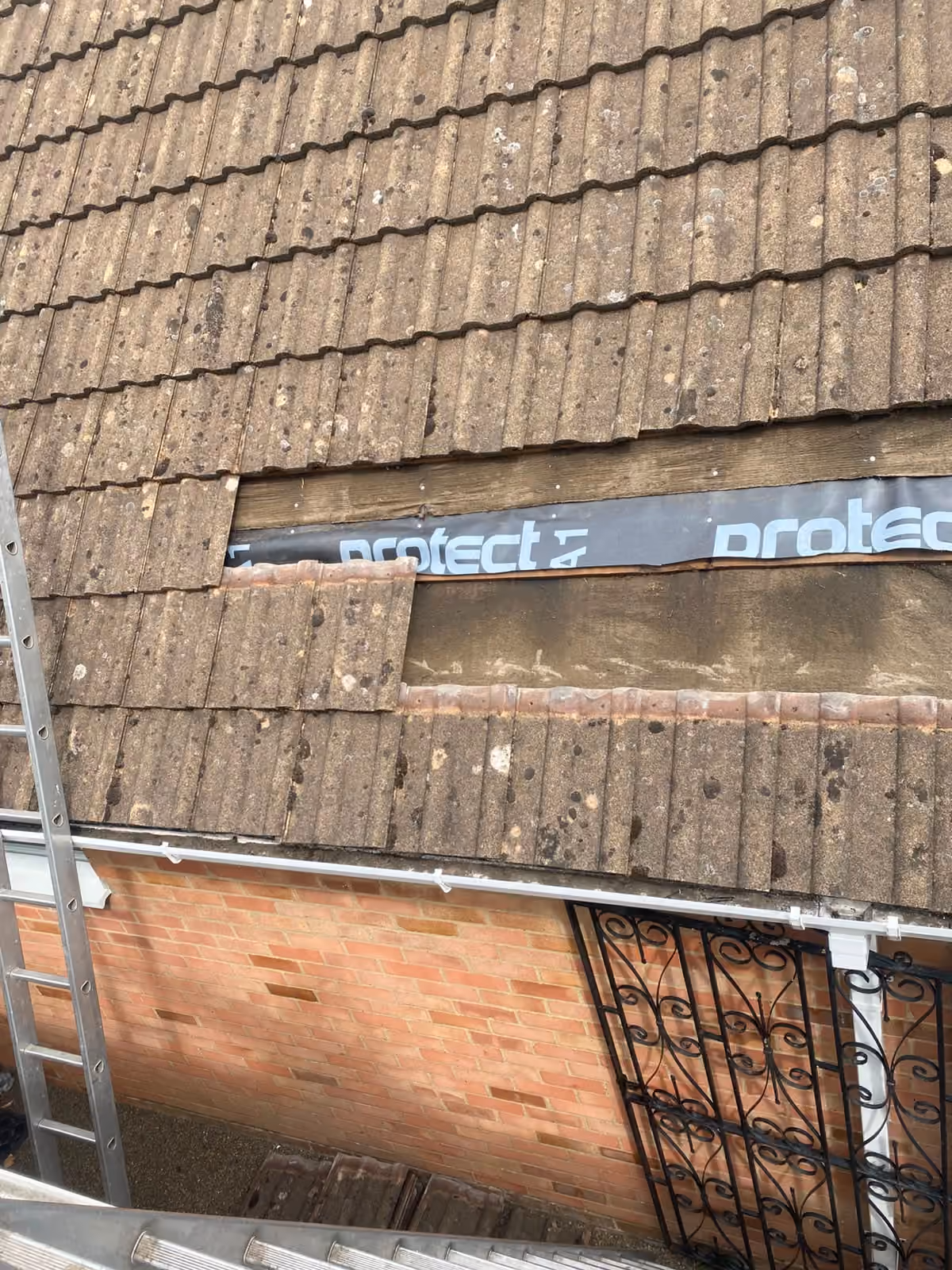 A tiled roof with a ladder up to the ridge