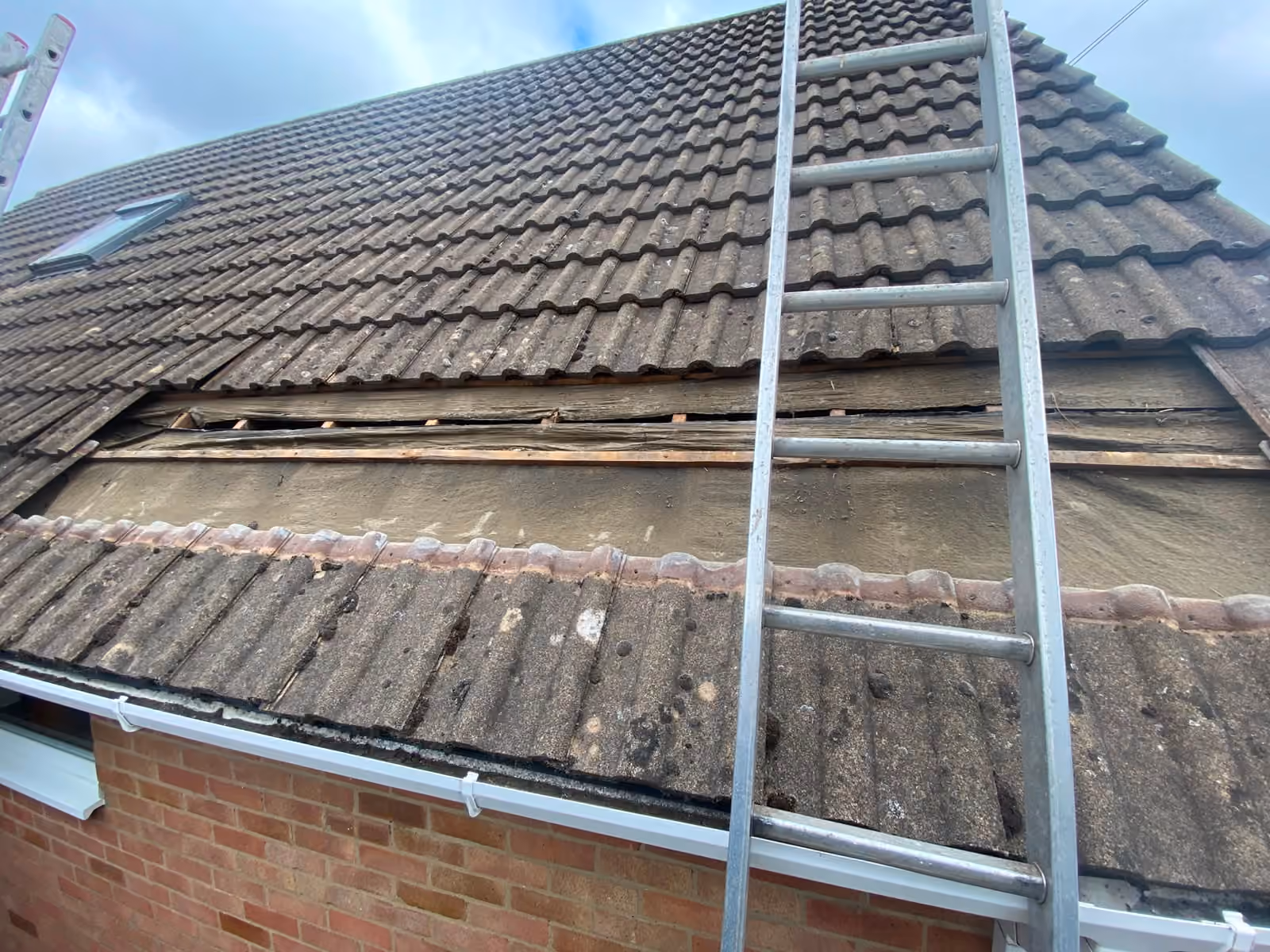 Tiled pitch with a ladder up, tiles being replaced course by course