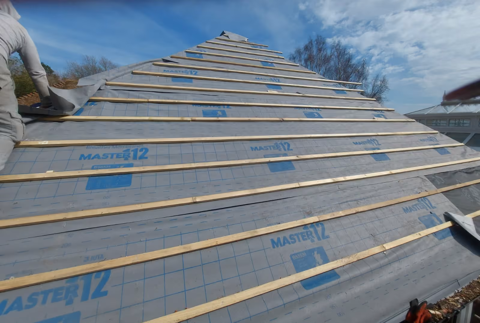 Breathable underlay run out across a hipped roof before battening