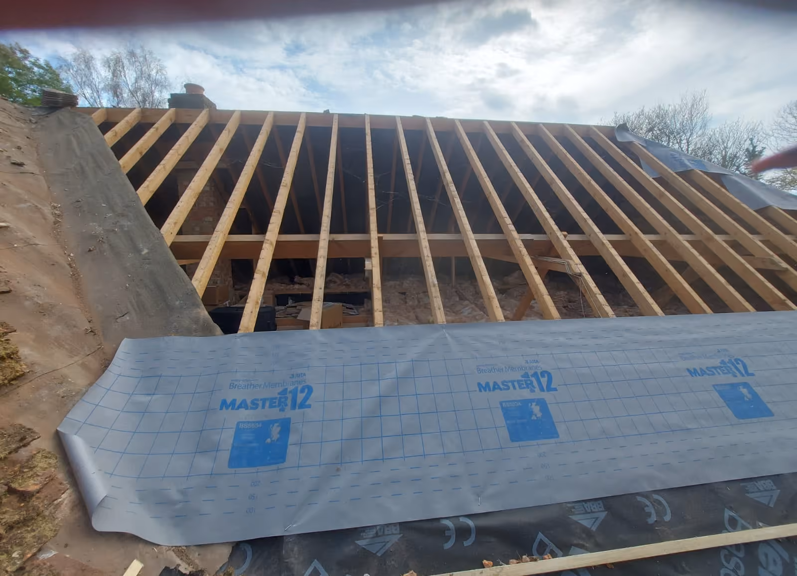 Rafters exposed after a full strip, underlay being drawn up the pitch